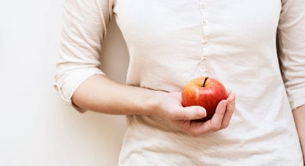 Eine Frau hält einen Apfel in der Hand.
